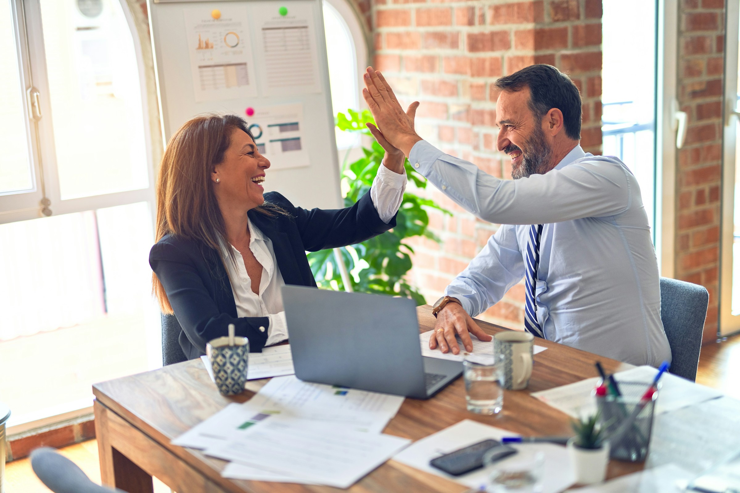 A business owner and her advisor celebrating with a high five